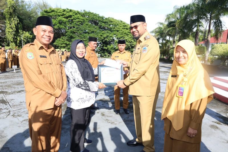 Bupati Hasan Ali Bassam Kasuba saat memberikan piagam penghargaan kepada tiga di Guru di halaman kantor Bupati, Senin (24/11/2025).